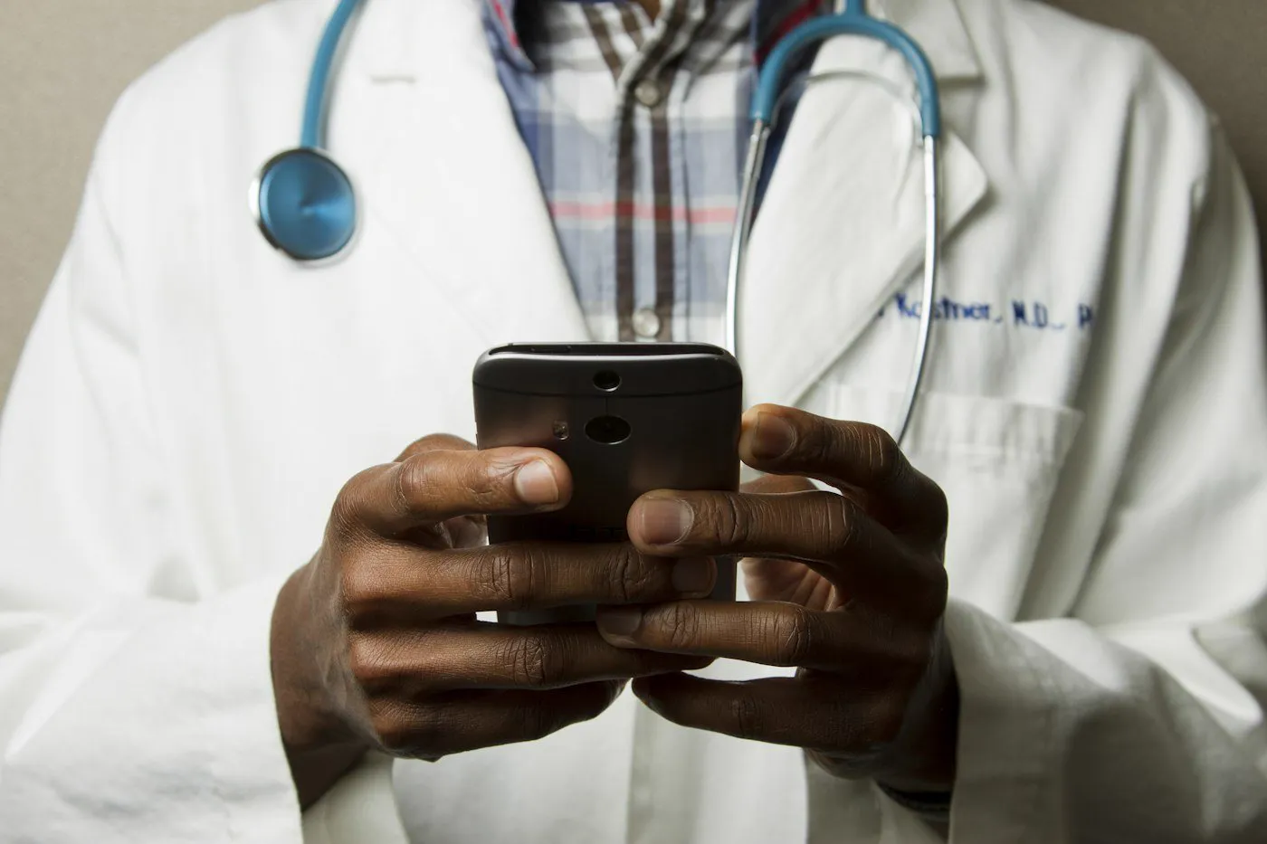 Médico de jaleco branco usando um celular